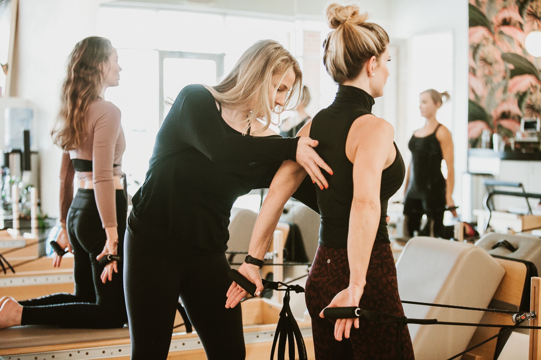 An instructor adjusting a client's form on the reformer