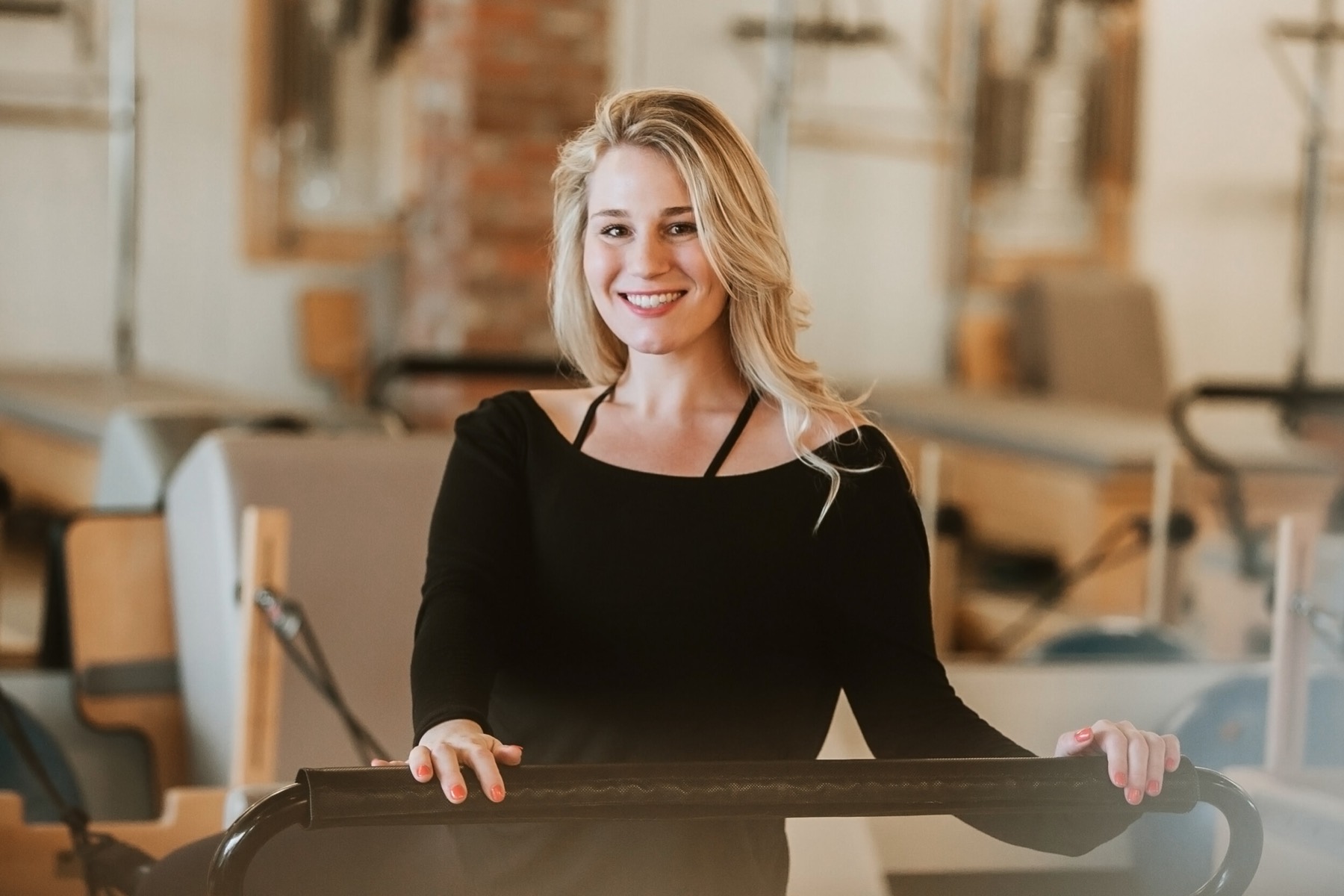 An instructor smiling beside a reformer